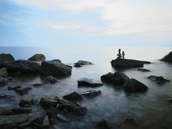 Rocks on sea shore against sky