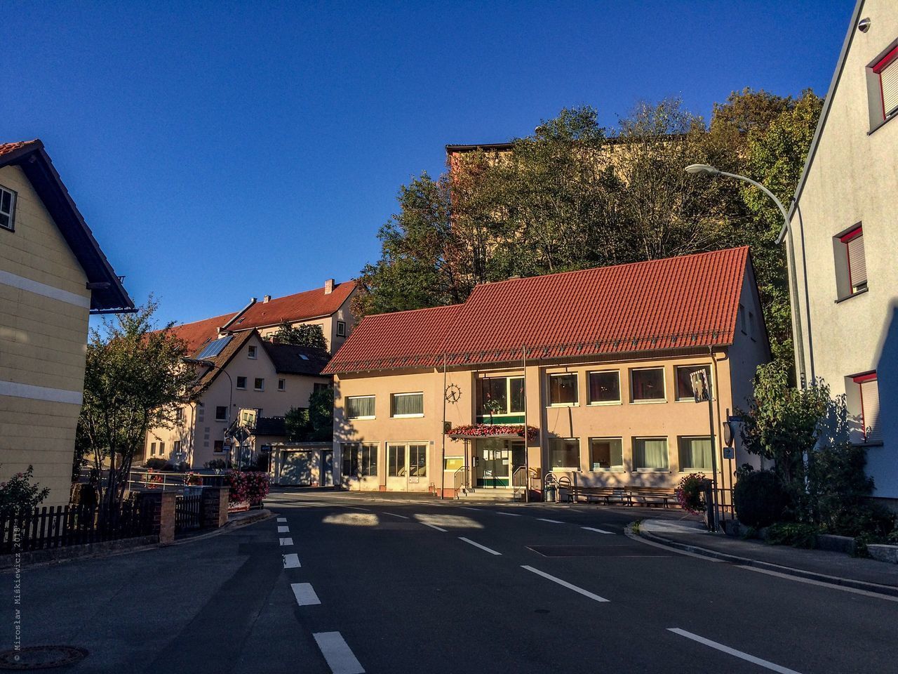 ROAD AMIDST BUILDINGS AGAINST CLEAR BLUE SKY