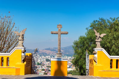 Cross on retaining wall in city