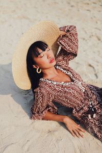 High angle view of young woman wearing hat sitting at beach