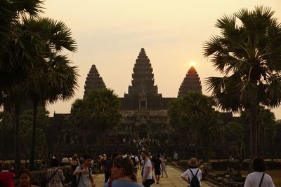 People at temple against sky during sunset