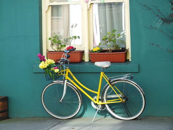 Yellow bicycle parked against green house