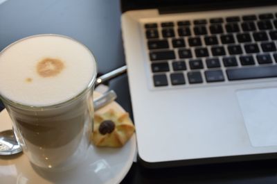 High angle view of coffee cup by laptop on table