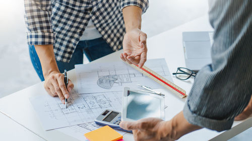 Midsection of architects working on plans at office