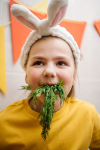Girl in rabbit ears eat herb dill vegetables easter copy space. high quality photo