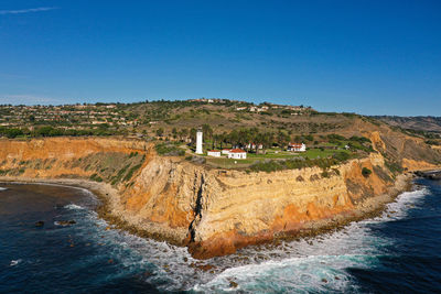 Scenic view of sea and buildings against clear blue sky