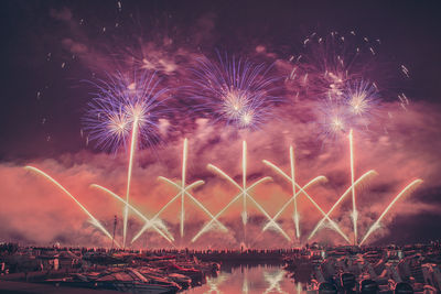 Firework display over river against sky