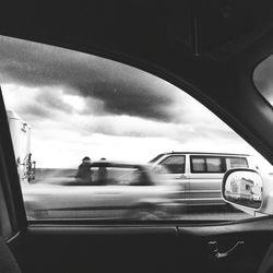 Cars on road against cloudy sky