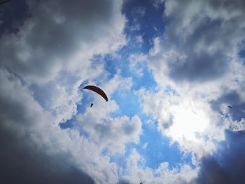 Low angle view of person paragliding against sky