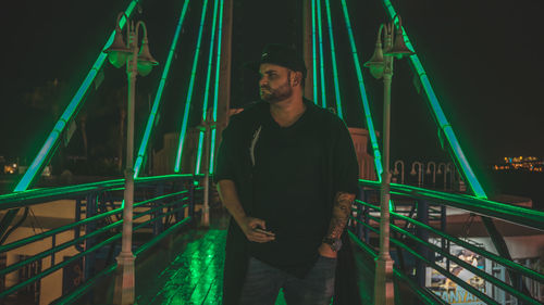 Portrait of young man standing in illuminated city at night