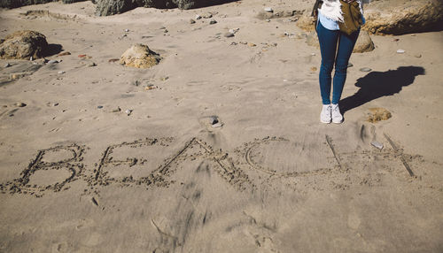 Low section of woman standing on sand at beach