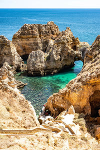 Scenic view of rocks on sea shore against sky