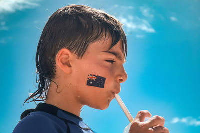 Close-up of young woman blowing bubbles against blue sky