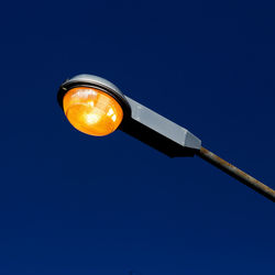 Low angle view of illuminated street light against blue sky