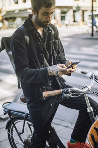 Businessman using smart phone while sitting on cargo bike
