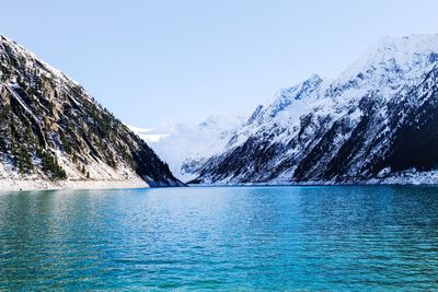 Scenic view of lake and snowcapped mountains against clear blue sky