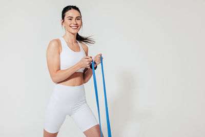 Portrait of young woman exercising against white background