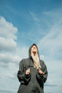 Full length of young woman standing against sky