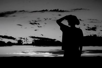 Silhouette man standing on shore against sky during sunset