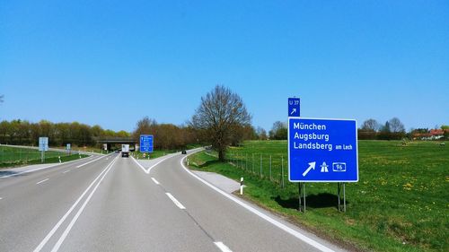 Road sign against clear blue sky