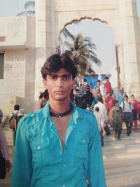 Portrait of young man standing against built structure