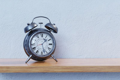 Close-up of clock on table against wall