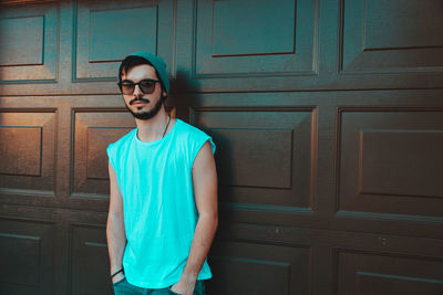 Portrait of young man standing against door