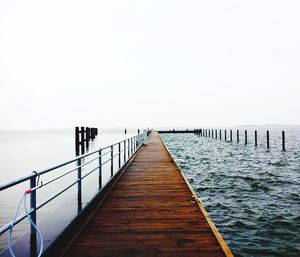 Wooden pier in sea against clear sky