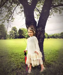 Portrait of girl standing against tree trunk at park