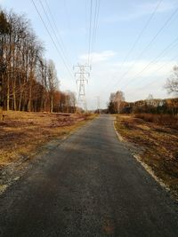 Road amidst trees on field against sky