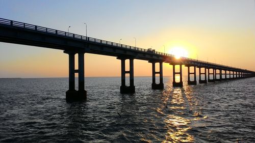 Bridge over sea at sunset