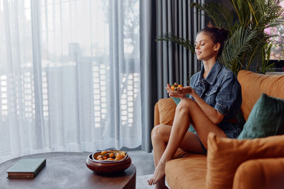Young woman using mobile phone while sitting at home