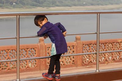 Side view of a boy standing by railing