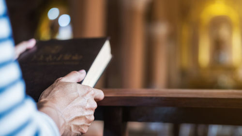 Midsection of man holding cross at home