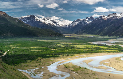 Aerial view of river flowing on land against mountain range