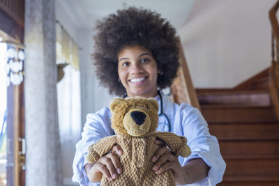 Portrait of doctor holding stuffed toy at home