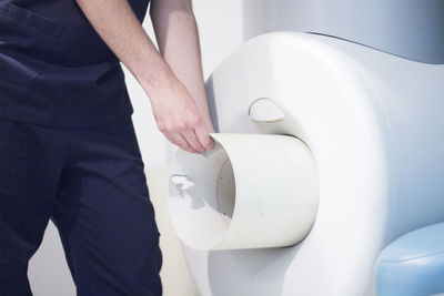 Midsection of man holding camera while standing in bathroom