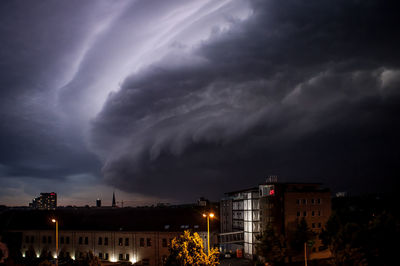 Illuminated city against cloudy sky