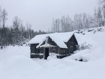 Snow covered houses and trees against clear sky