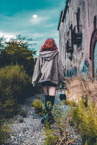 Rear view of woman with umbrella standing against plants