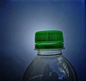 Close-up of glass bottle on table against blue background