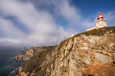 Low angle view of lighthouse on mountain against sky