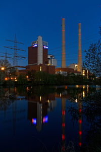 Illuminated city by river against sky at night