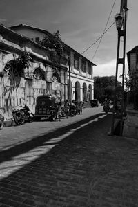 Road by buildings in city against sky