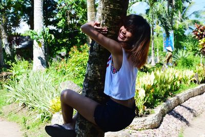 Smiling woman climbing tree at park