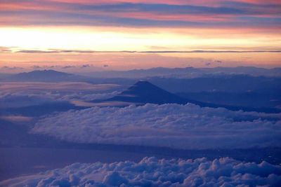 Scenic view of landscape against cloudy sky at sunset