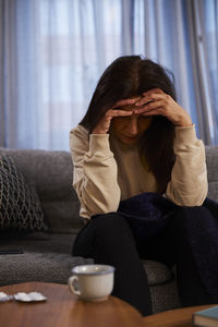 Woman sitting on sofa with headache