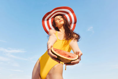 Portrait of young woman wearing hat against sky