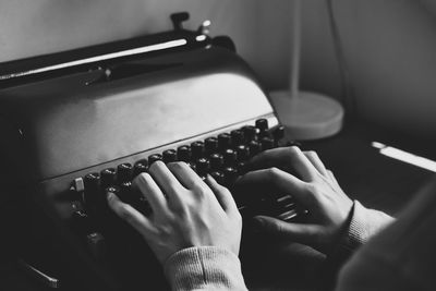 Cropped hand of person typing on typewriter