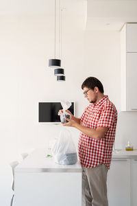 Young man using mobile phone while standing at home